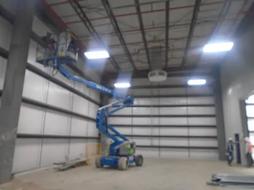 Operario en plataforma elevadora realizando trabajos en altura dentro de nave industrial. Es esencial saber Qué es el mantenimiento industrial.