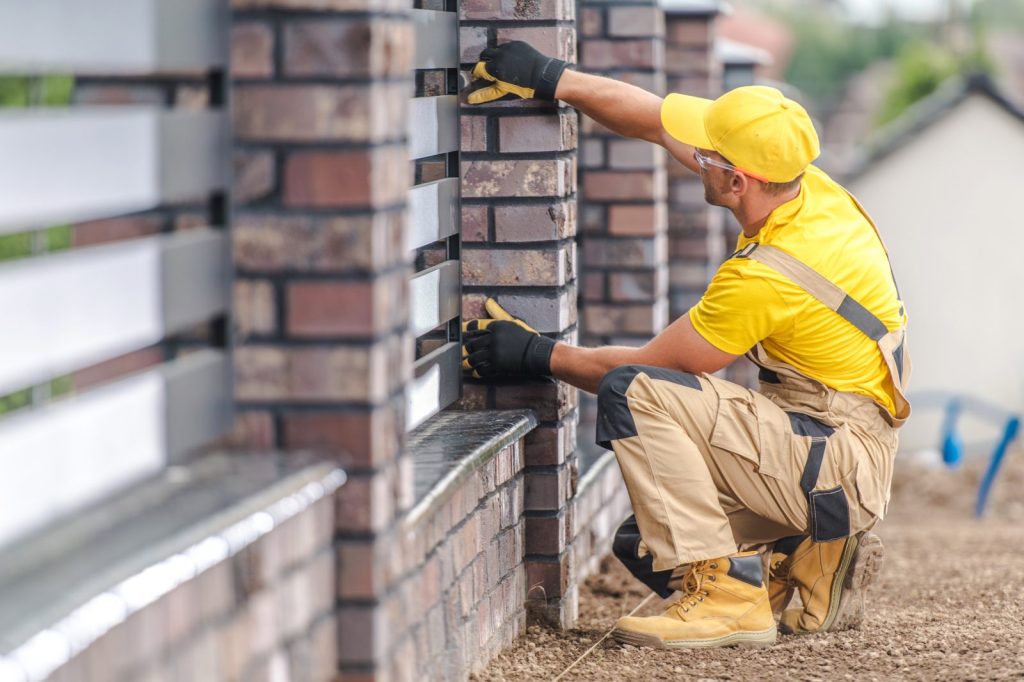 Trabajador de GRUPO S3 ejecutando albañilería profesional en el detallado de un muro de ladrillo exterior.